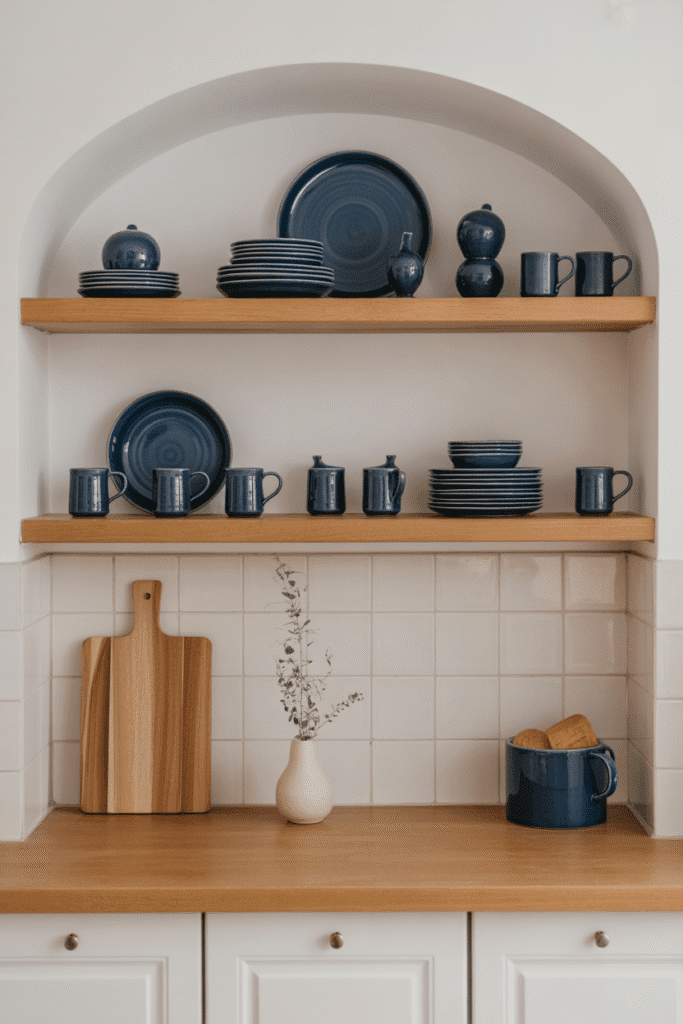 Blue accessories on open shelving add subtle color to a white kitchen.