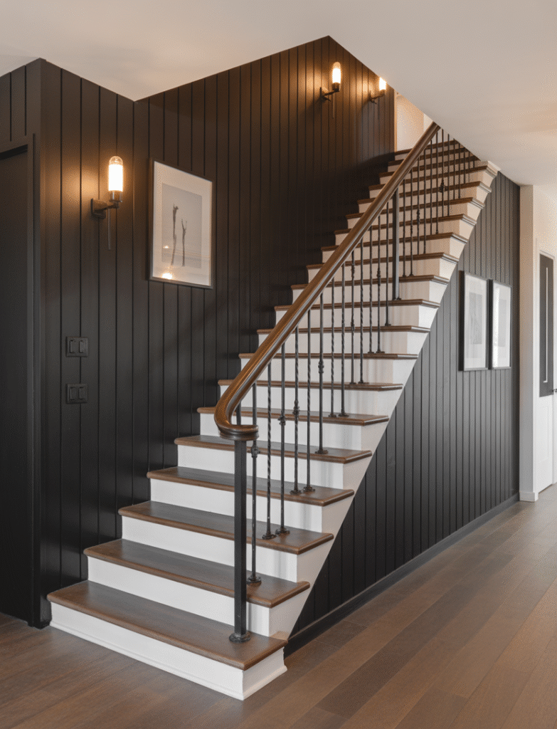 Staircase with black board and batten walls, paired with sleek iron railings, wood treads, and minimalist wall sconces, turning a forgotten space into a showstopper.