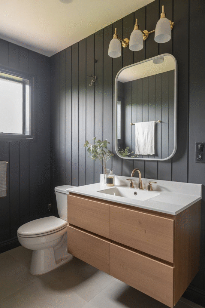 Modern bathroom with dark charcoal board and batten walls, gold hardware, white sink, and light wood vanity.