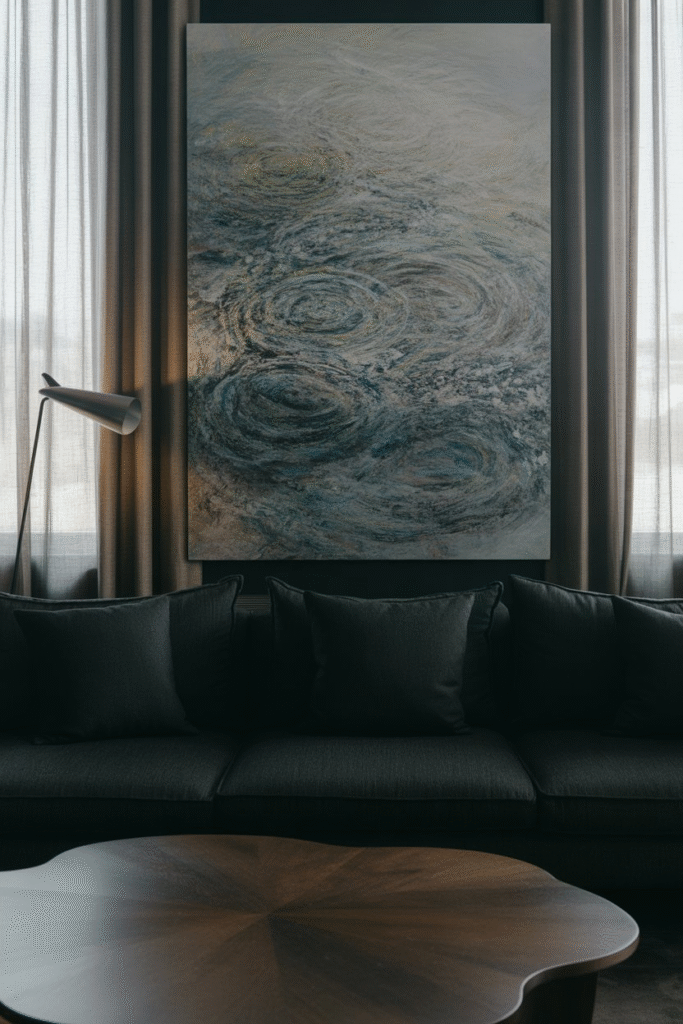 Oversized abstract art hangs above a moody sofa, creating a bold visual statement in a dark living room.