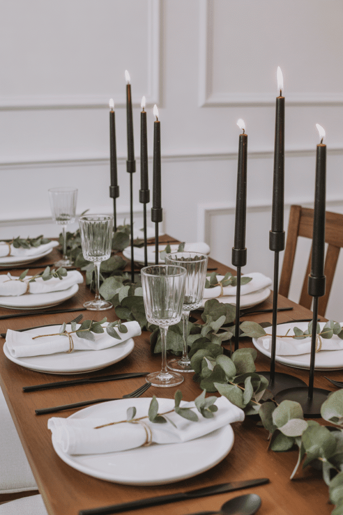 Minimalist Thanksgiving table with eucalyptus greenery and black candleholders.