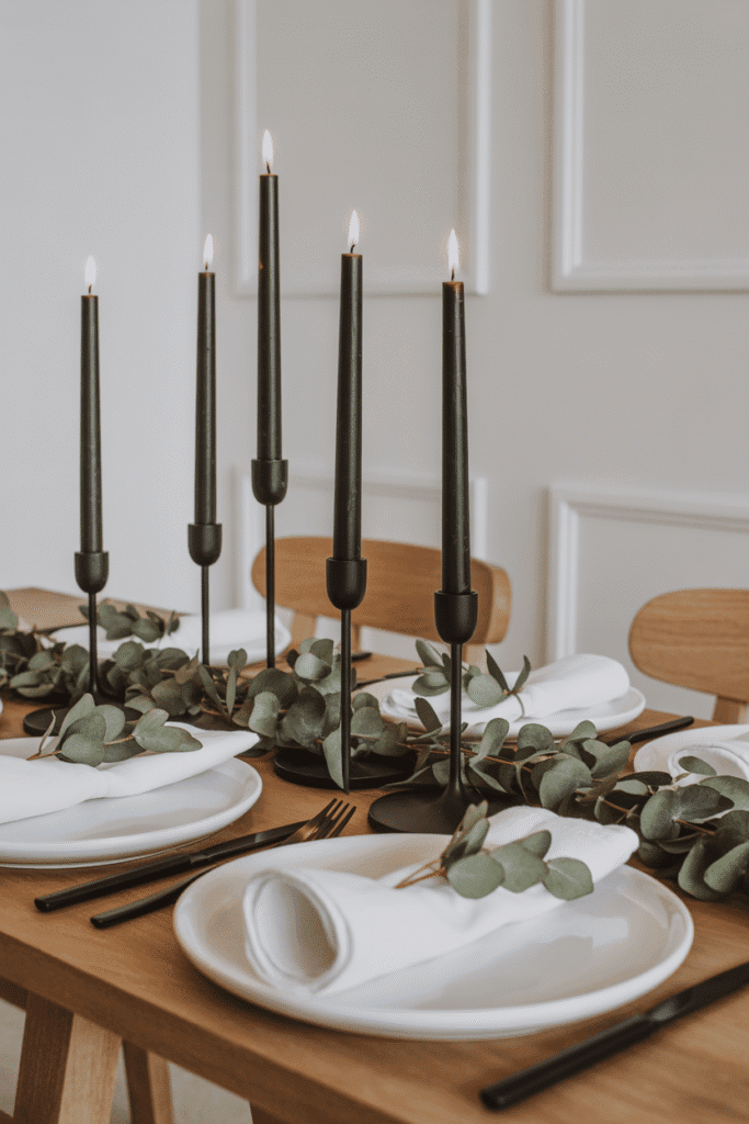 Minimalist Thanksgiving table with eucalyptus greenery and black candleholders.