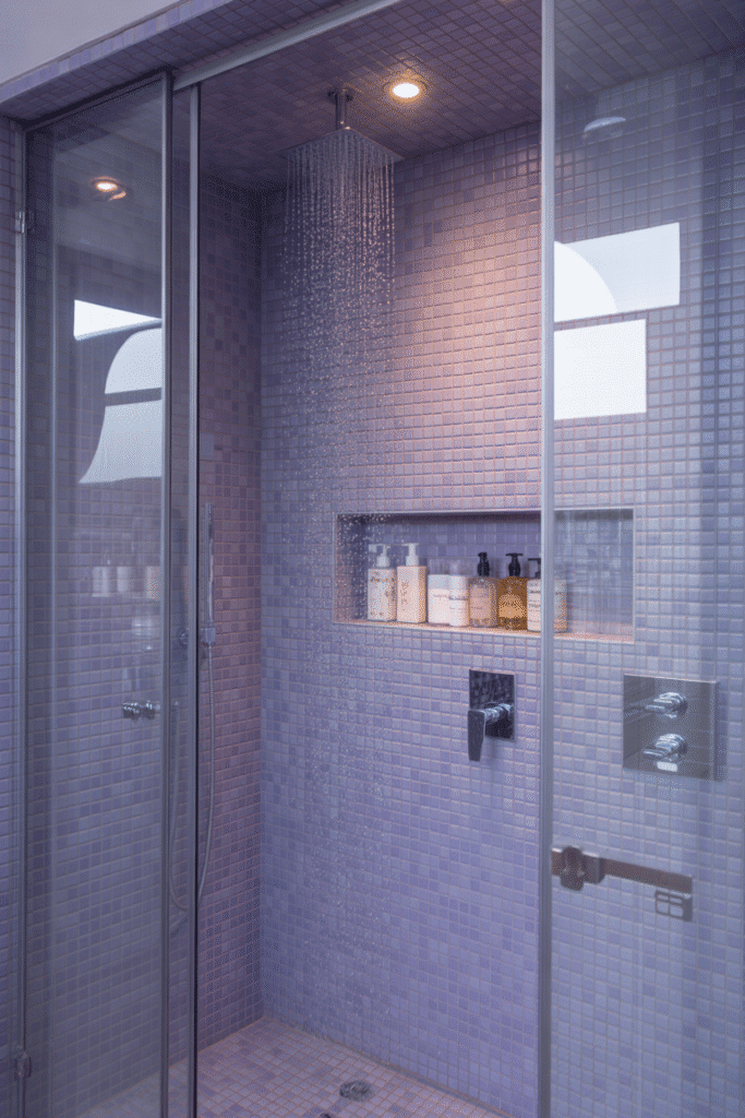 A dazzling bathroom shower featuring rich purple mosaic tiles that add texture and elegance.