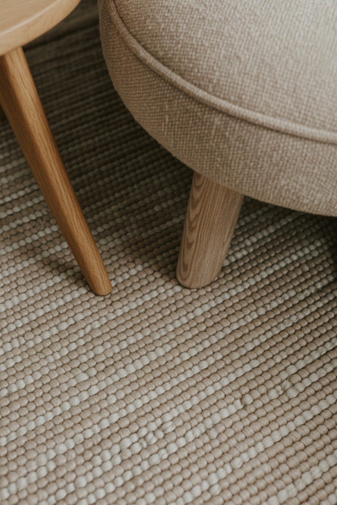 Textured wool rug detail under wooden furniture creating cozy layered look.