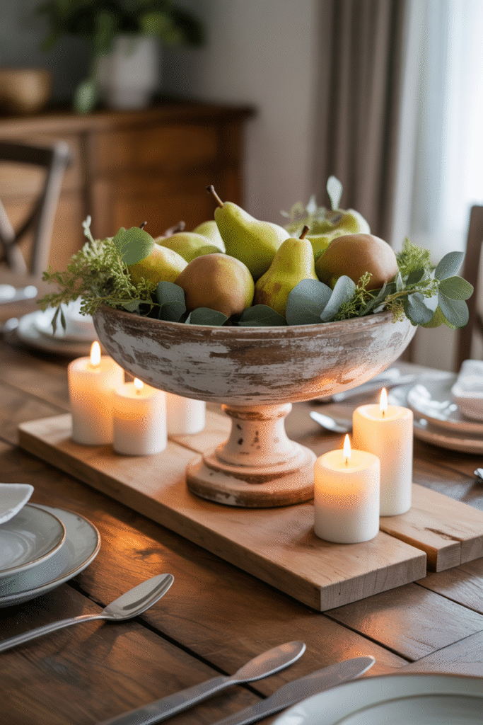 Rustic French farmhouse table with large centerpiece of fruit bowl and candles.