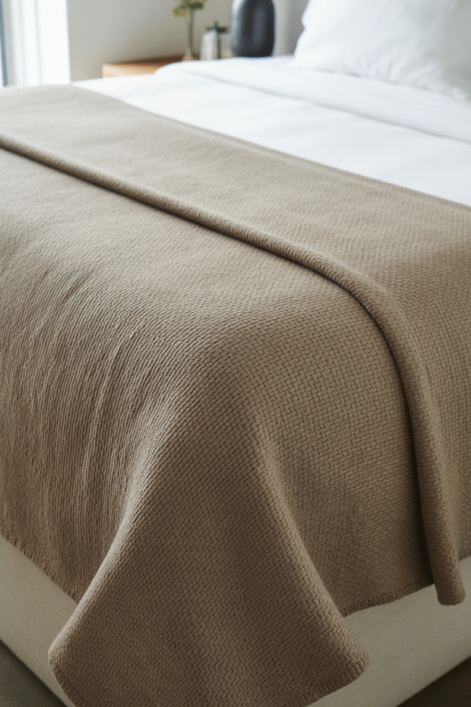 Tailored bed styling showing a blanket neatly tucked under the mattress with crisp, mitered corners for a clean geometric finish.